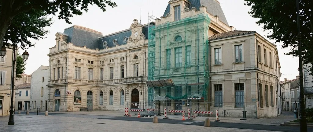 Façade d'un hôtel de ville en rénovation, échafaudage et barrières de chantier sur la place, tôt le matin